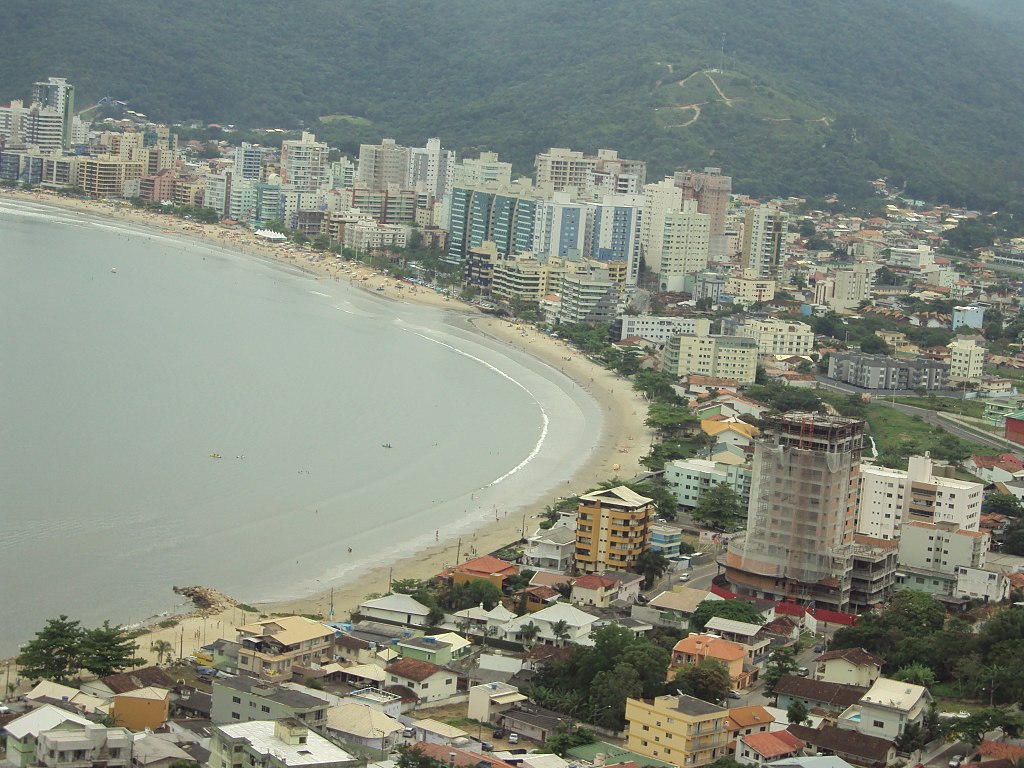 Imagem panorâmica da orla de Itapema, destacando prédios residenciais modernos e mar cristalino, típica da região da Costa Esmeralda.