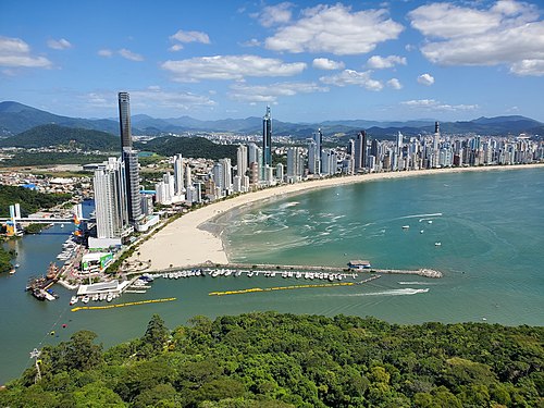 Balneario camboriu Vista aérea de Balneário Camboriú com arranha-céus à beira-mar e orla movimentada, mostrando a infraestrutura de alto padrão da cidade.
